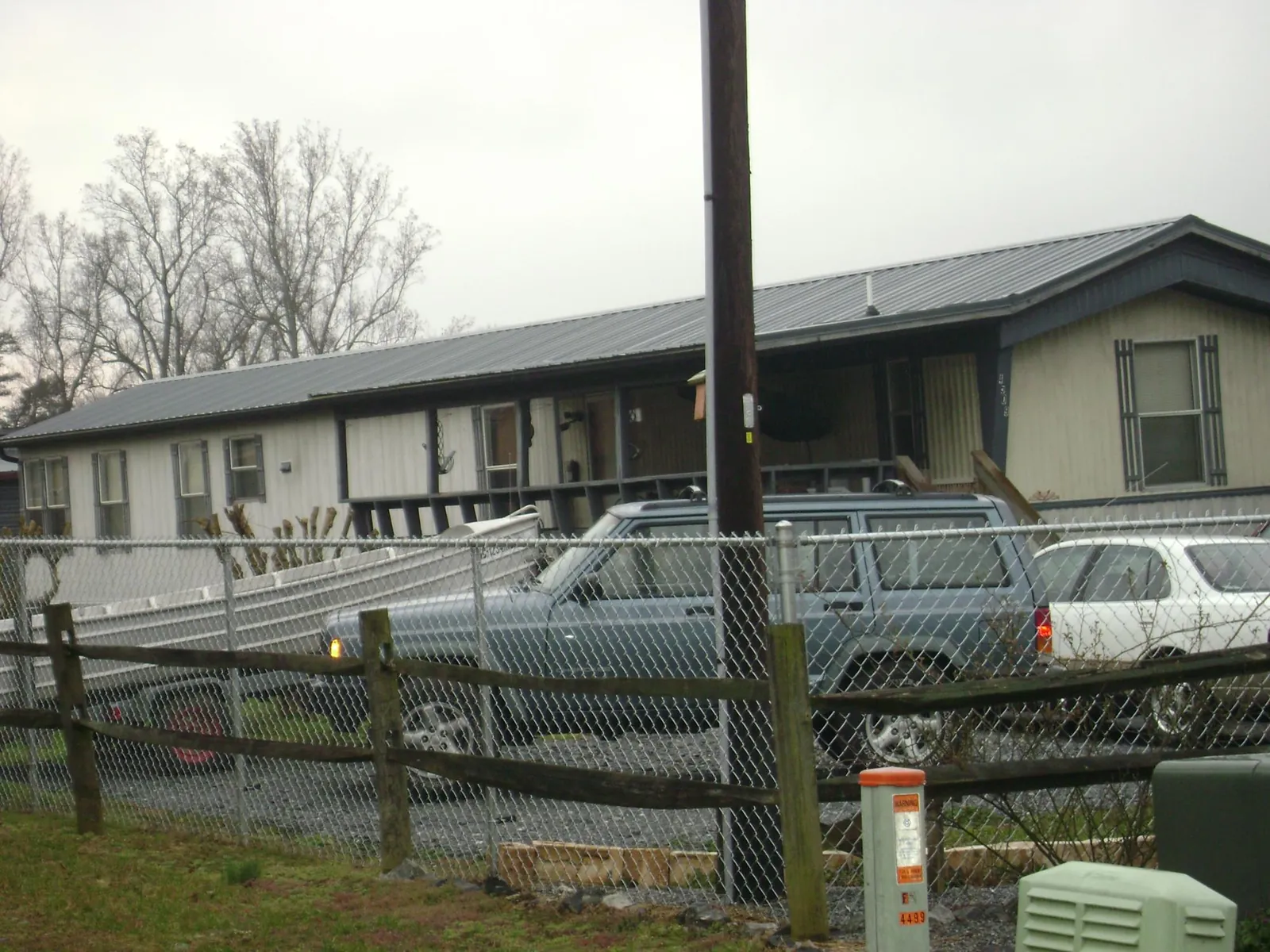 Dark metal roof on a long single story building behind a chain link fence in Astoria