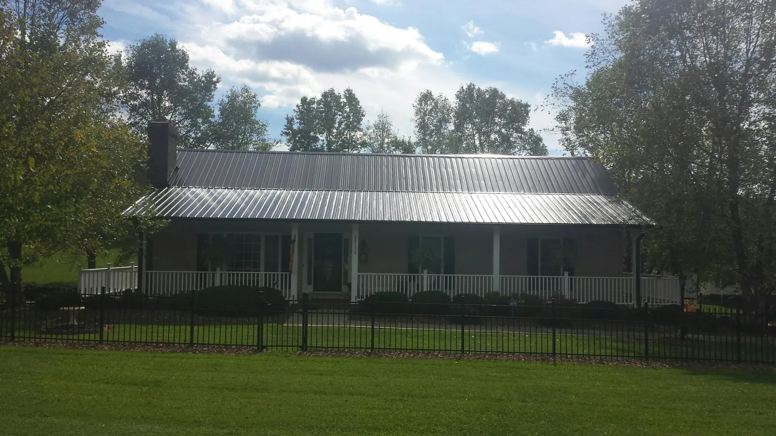 Gray metal roof on a brick ranch with a full width front porch — Gutter Guard Installation work by our crew in Astoria